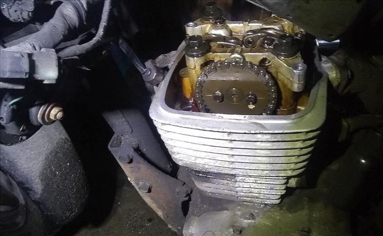 The engine has the rocker cover off showing the oily and light brown tappets