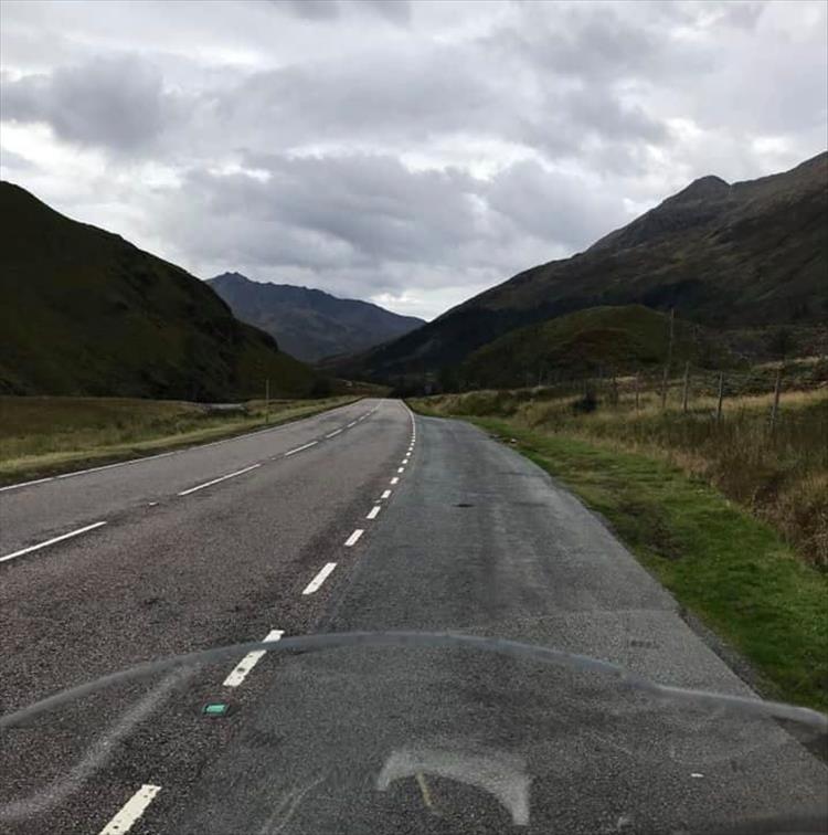 Looking over the screen we see the road heading off between dark mountains and cloudy skies