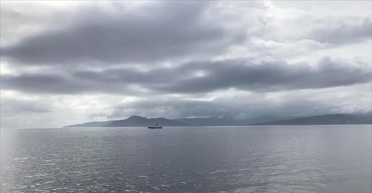 Calm flat waters, grey wet skies and a lonely boat on the waters seen from the ferry