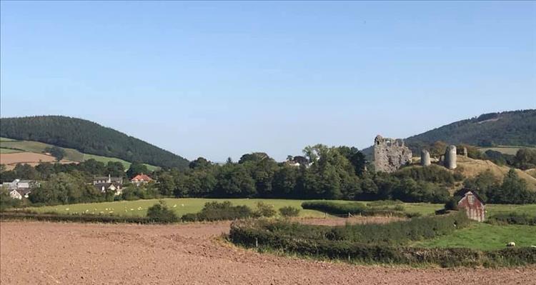 Castle ruins on a small hillside among the rolling hills and fields in Wales