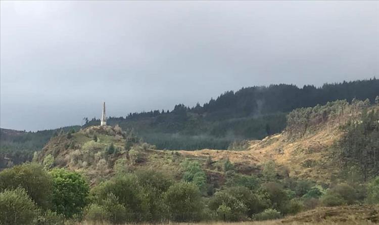 An angular and jaunty landscape with some kind of pointed monument in the scene