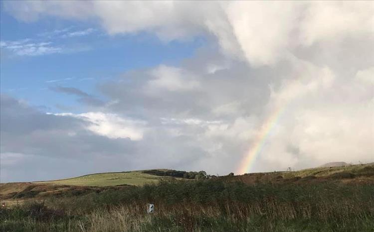 A rainbow set against the clouds and rugged landscape at Port Ban campsite