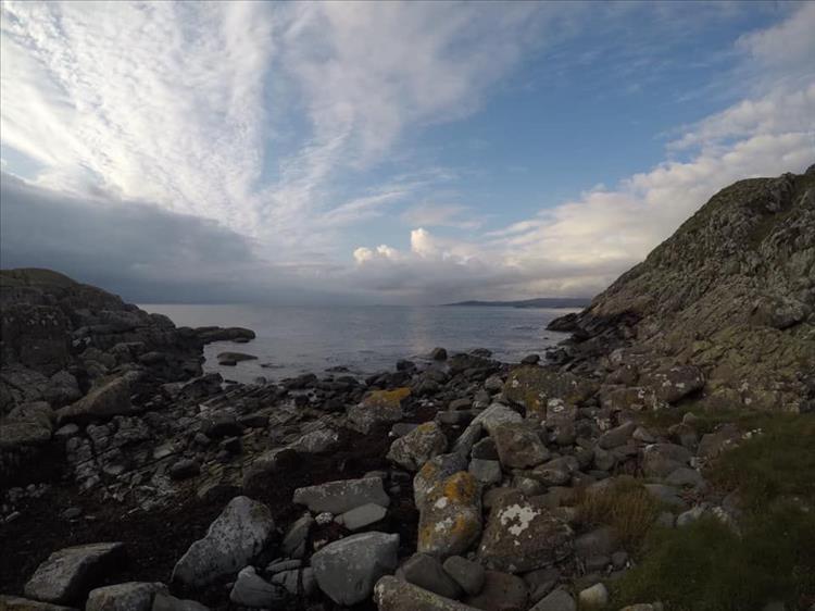 Rocks and boulders form a v shape leading down to the sea in a dramatic scene