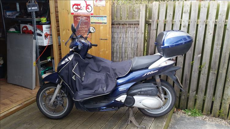 Boogers sh300 honda scooter outside his shed with a material leg cover fitted