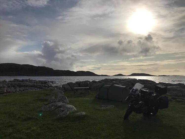 In darkening skies we can make out Andy's tent, motorcycle and the rugged shoreline at the campsite