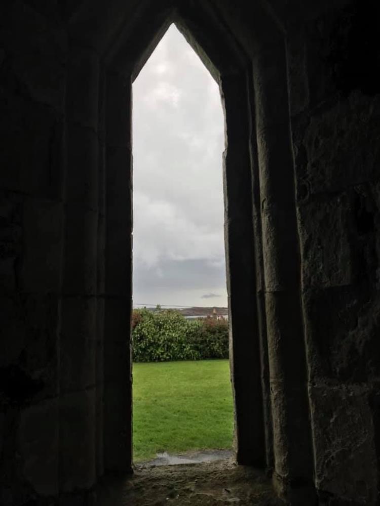Looking through the tall narrow slit window out to the countryside beyond the abbey