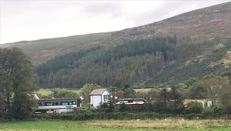 Big fat hills, nestled in the valley is are the old train carriages and signal box of Rogart