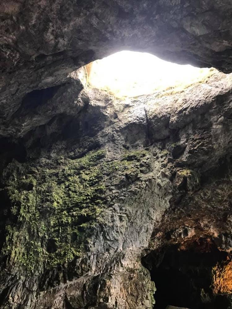 Looking upwards we see a rough hole in the top of the craggy cave where the light pours in