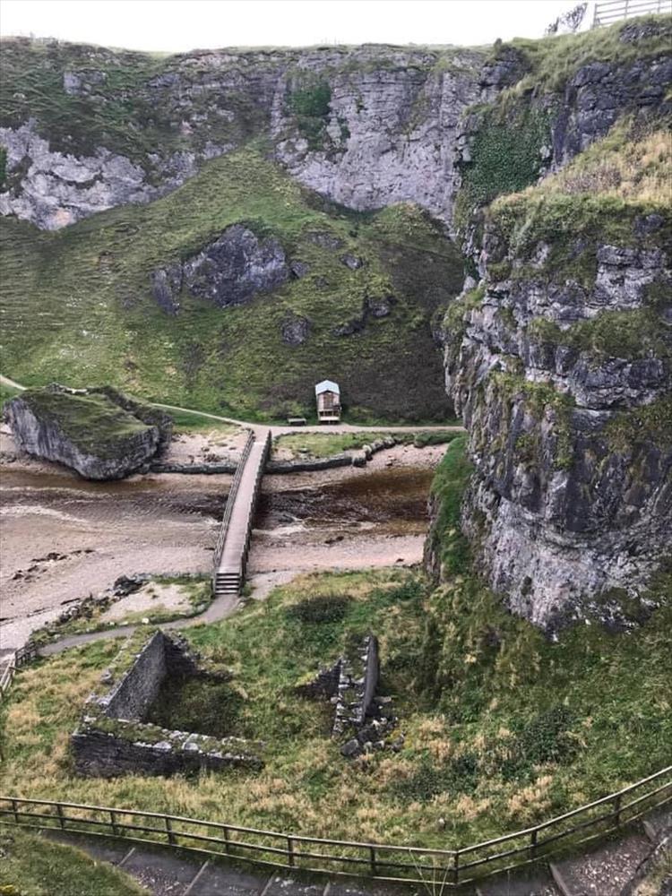 Looking down into the steep and rocky cove with the mouth of smoo cave at the bottom