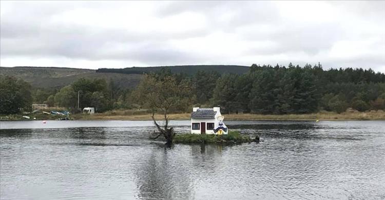 A small, doll size house on a tiny island in the middle of a lock, the wee house