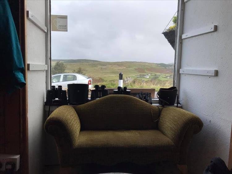 Lookin to the window we see an old settee, binoculars on the windowsill and the hills