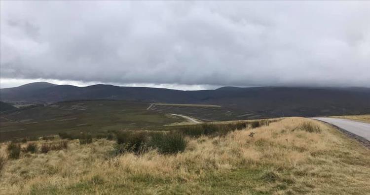 The road wriggles its way through the huge yet mor rounded hills of the Cairngorms