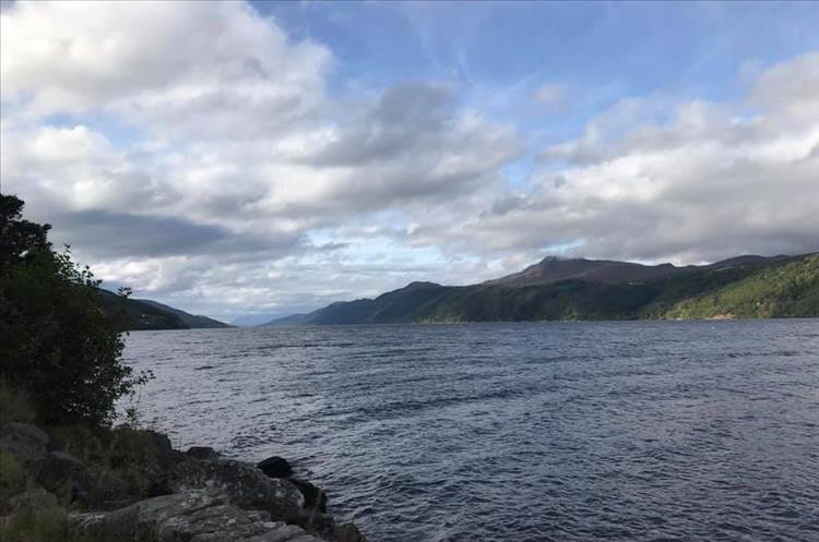 Loch Ness we see the waters and the surrounding mountains falling steeply into the loch