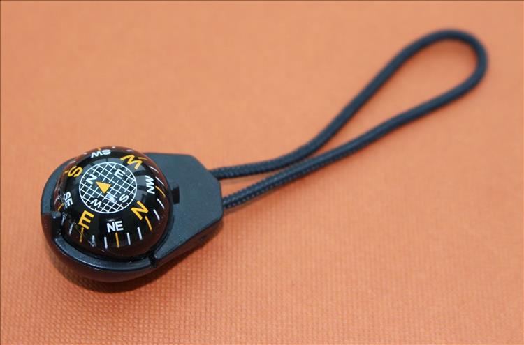 A small compass on a short length of string designed to be fitted to a zipper pull