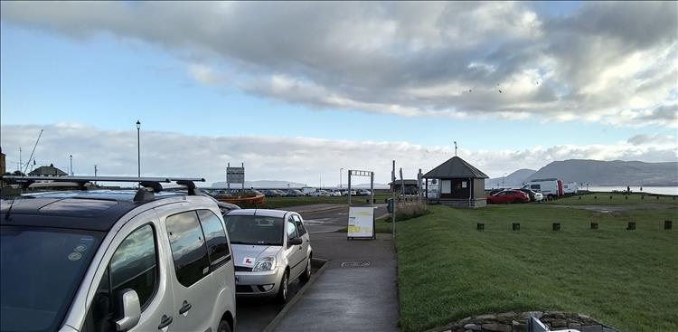 Looking across we see cars on a road, a large green area and the snowdonian mountains in the distance