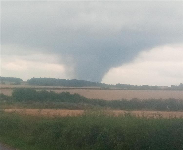 Over the horizon rises and spreads out a great plume or perhaps a vast tornado