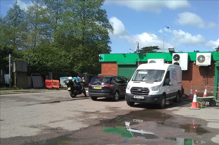 At a regular petrol station behind we see green trees and blue skies