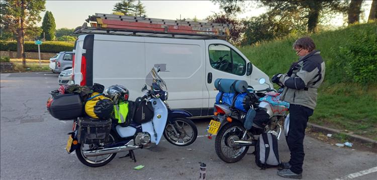 A chap stands by his CG125 and Bogger's C125 in a car park.