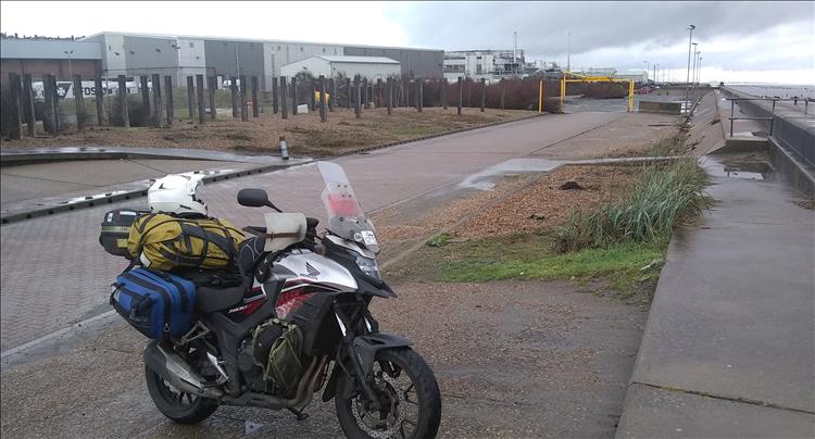 Ren's bike with camping gear at Ness Point, there's a large industrial area in the background