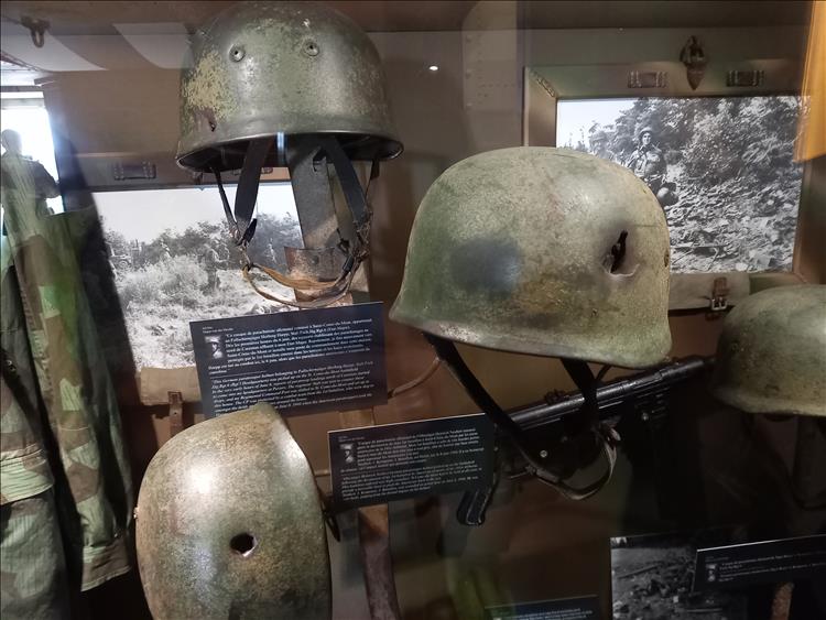 Various World War 2 helmets many with bullet holes in them