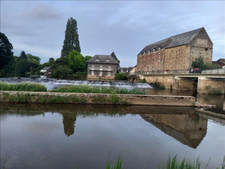 Lush trees, calm river, a weir and ancient buildings in Malestroit