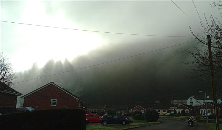 We see the sun in the sky but the houses are in the shade of a hillside