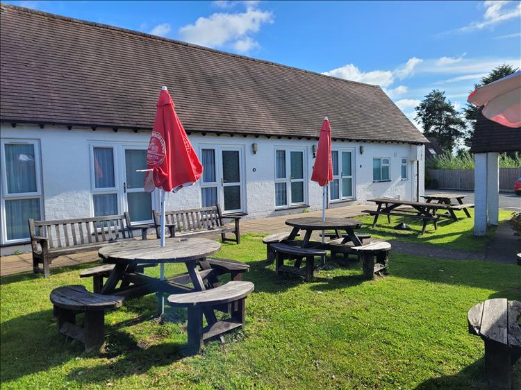 A long row of rooms or chalets painted white behind the pub