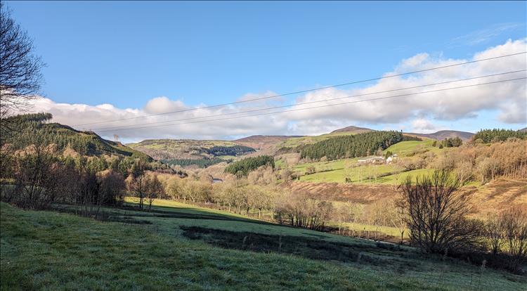 clear skies, rolling countryside, trees, fields and hills along the A5 through Wales
