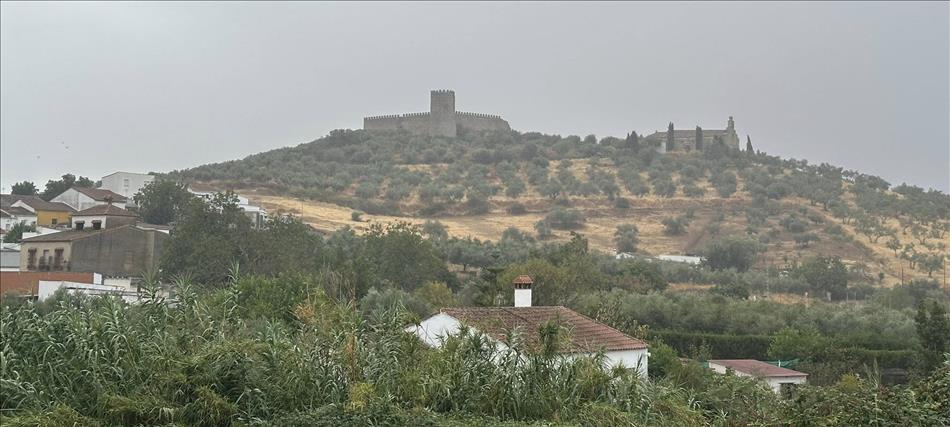A moorish castle atop a hill, a church close by and a town in the foreground
