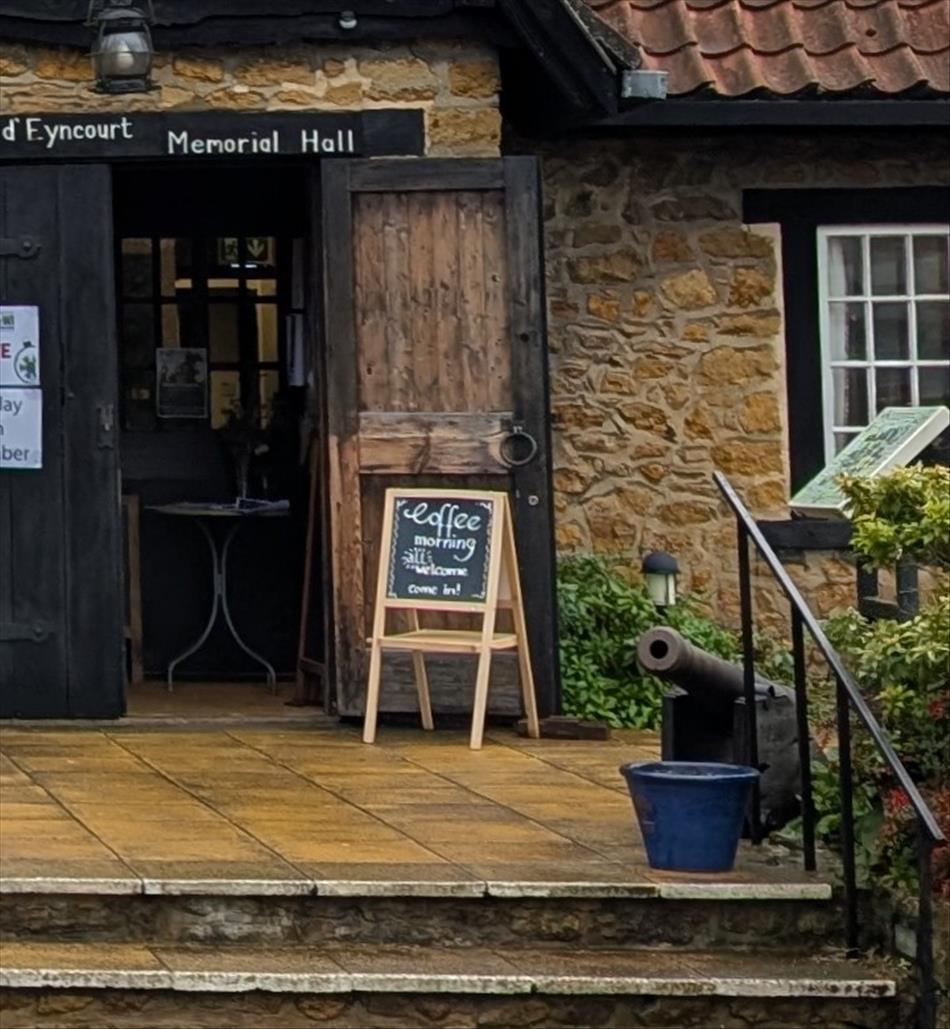 The doorway to the old building, now the local village hall. A sign reads coffee morning all welcome