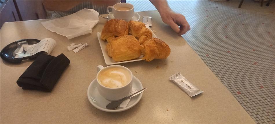 A cafe table, coffee in cup and a plate with pain au chocolats