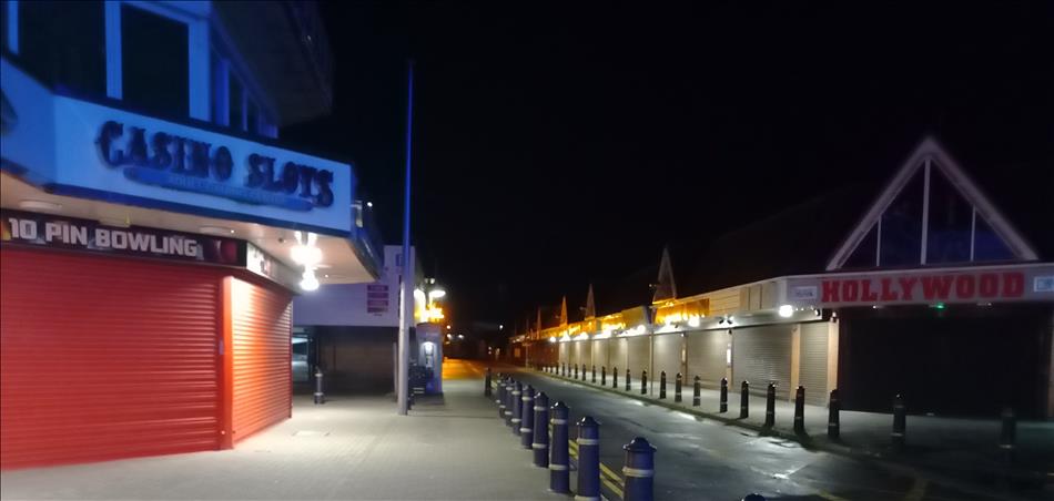 A street of shuttered shops with signs like arcade and slot machines all closed up in the dark night