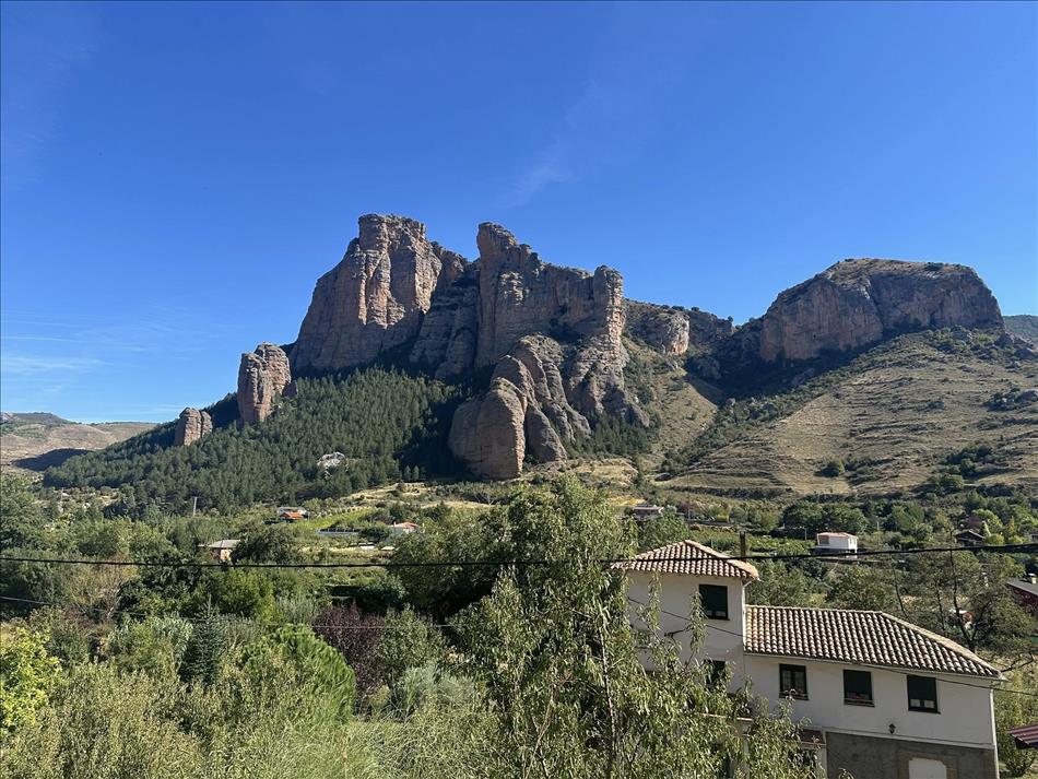 A few houses. behind are towering rocks that look like they're sandstone