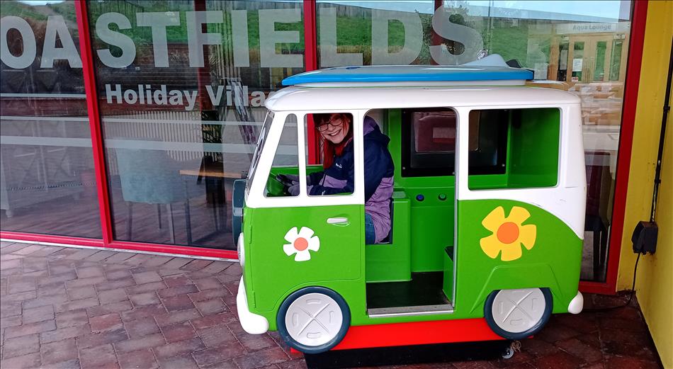 Sharon squeezed into a childs toy van ride thing with a silly grin on her face