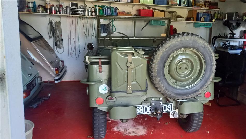 A willys Jeep in army green, we can just see the rear of a couple of citroen Dianes too
