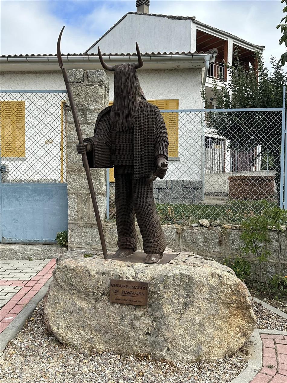 Sculpture of man with hair over his face and bull horns in some brown metallic material