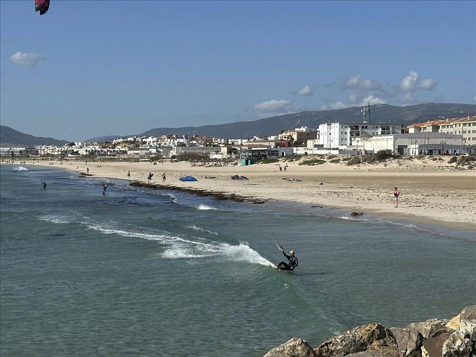 Kite surfers in the water's edge, the beach and white buildings and apartment blocks
