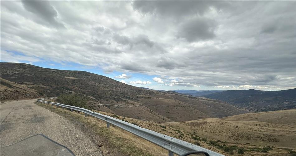Seen from the bike a road wendles it's way down between folds of rolling hills streching into the distance
