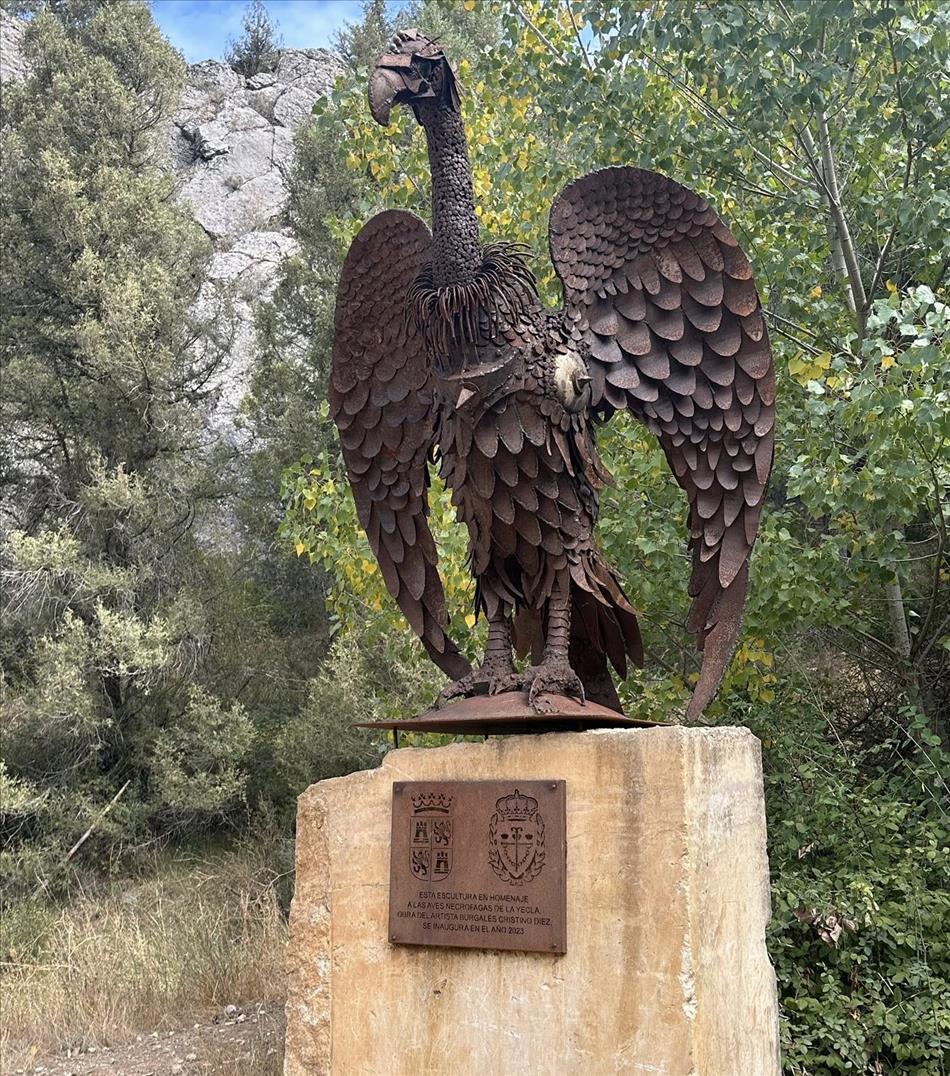 A steel artistic vulture on a plinth among the rocks and trees