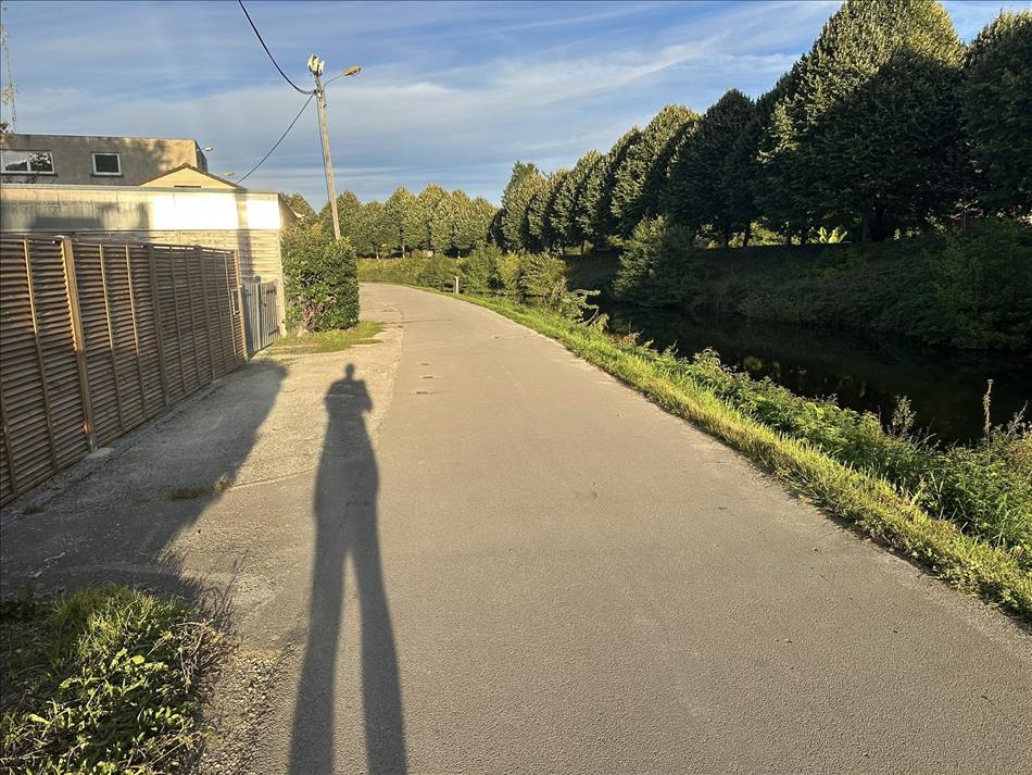 A slim river or canal, towpath, houses, and Andy's shadow stretching out a long way