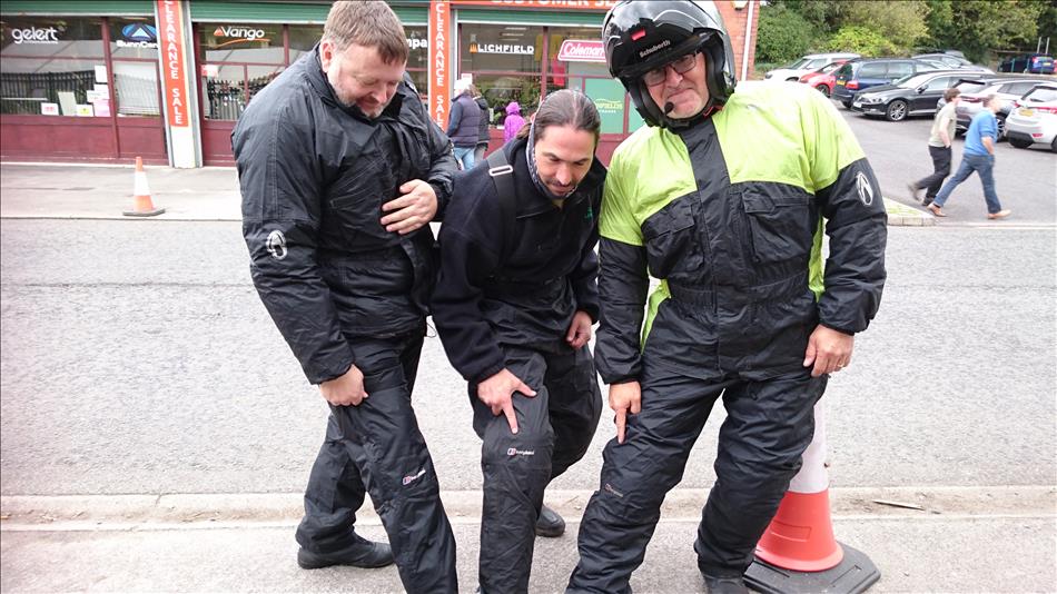 3 riders in waterproof bike gear all point to the "Berghuas" logo on their pants