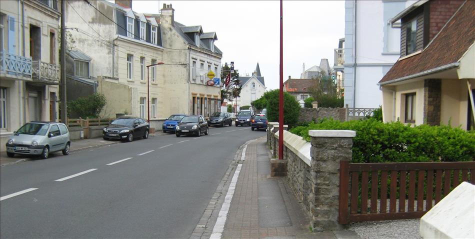 A typical french town with houses and balconies and a street with a few cars