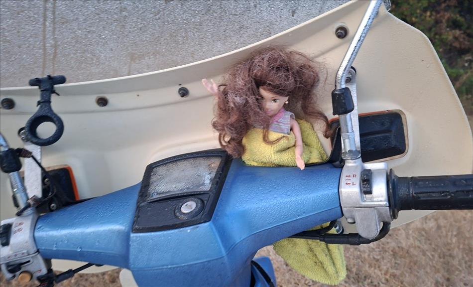 A small female doll tucked between the handlebar and screen on Boggers C90