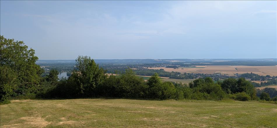 A field, trees, vast open plains, hills in the far far distance, and a glimpse of a broad river between trees