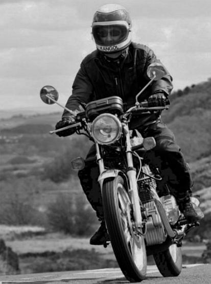 A black and white image of a 250 superdream being ridden over hills