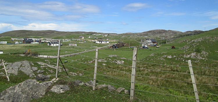 A small collection of white houses nestled close to the shore in the Highlands