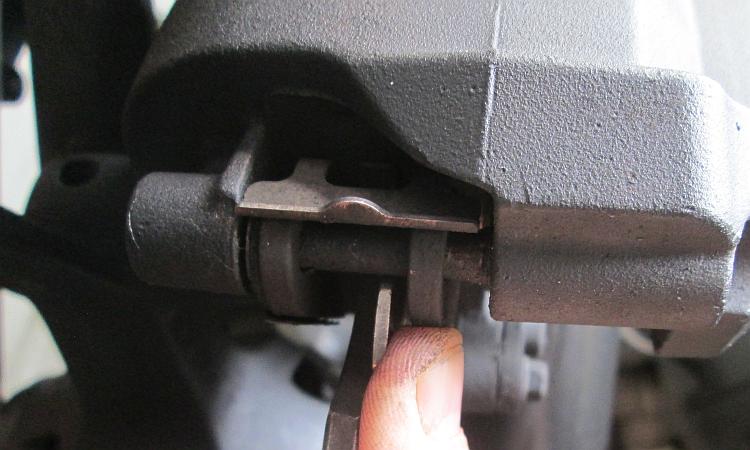 Using a 20 pence coin to check the thickness of the front brake pads